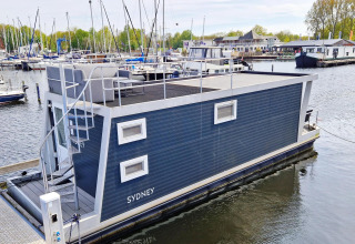Moderne woonboot Havenlodge N in Marina Parcs Naarden in Nederland, aangemeerd aan een steiger.