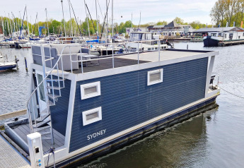 Modern houseboat named Havenlodge N at Marina Parcs Naarden in the Netherlands, docked in a marina.