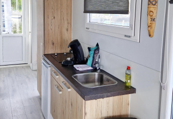 Køkkenområde på en husbåd, Havenlodge N, med træfinish, vask, kaffemaskine og vindue ved Marina Parcs Naarden.