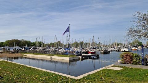 Exclusieve glampingplek met zwembad en zicht op een haven vol zeiljachten.