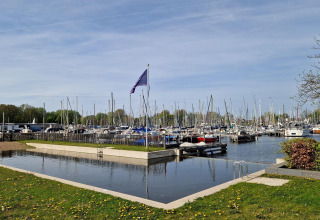 Exclusieve glampingplek met zwembad en zicht op een haven vol zeiljachten.