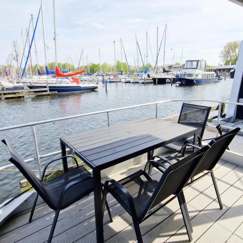 Buiten tafel en stoelen op een woonboot in Marina Parcs Naarden met zicht op de jachthaven in Nederland.