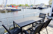 Buiten tafel en stoelen op een woonboot in Marina Parcs Naarden met zicht op de jachthaven in Nederland.