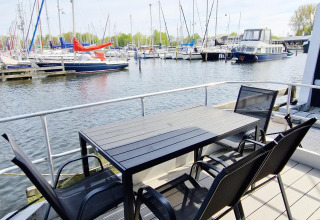 Buiten tafel en stoelen op een woonboot in Marina Parcs Naarden met zicht op de jachthaven in Nederland.
