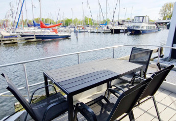 Terrasse einer Hausbootwohnung mit Tisch und Stühlen am Hafen von Marina Parcs Naarden, Niederlande.