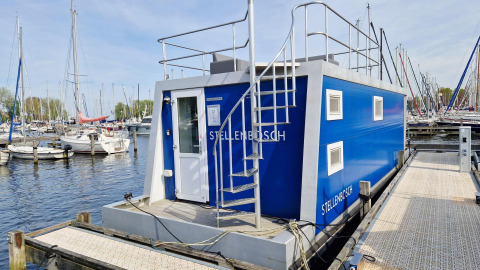 Woonboot Havenlodge N aan Marina Parcs Naarden in Nederland, omringd door aangemeerde zeilboten.