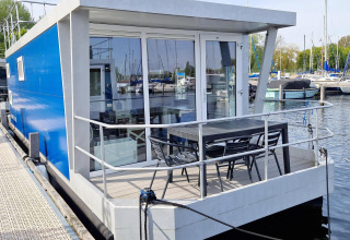 Moderne husbåd ved Marina Parcs Naarden i Holland, med blå ydre og terrasse med havemøbler.