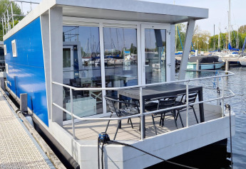 Moderne husbåd ved Marina Parcs Naarden i Holland, med blå ydre og terrasse med havemøbler.