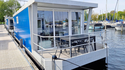 Modern houseboat Havenlodge N at Marina Parcs Naarden, Netherlands, with waterside terrace seating.