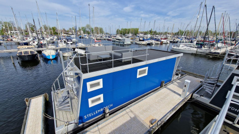 Woonboot Havenlodge N bij Marina Parcs Naarden, Nederland, met jachten en steigers eromheen.