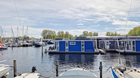 Vista de la casa flotante Havenlodge N en Marina Parcs Naarden, Países Bajos, en un día soleado.