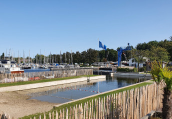 Alojamiento glamping con piscina, palmeras y vista al puerto deportivo con barcos en un día soleado.