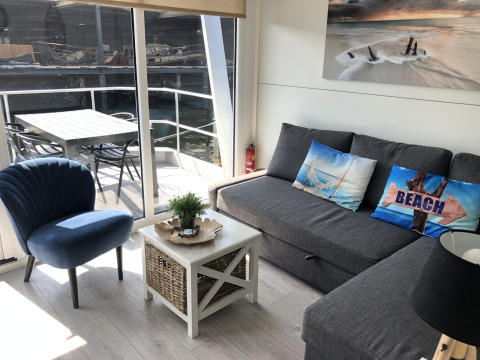Salón moderno de casa flotante en Marina Parcs Naarden, Países Bajos, con vista al agua y zona exterior.