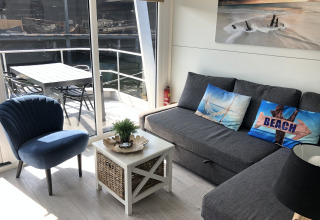Modern houseboat living area at Marina Parcs Naarden, Netherlands, with view of water and outdoor seating.