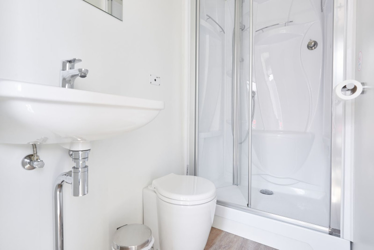 Baño moderno en una casa flotante con lavabo blanco, inodoro y ducha, diseño minimalista y luminoso.