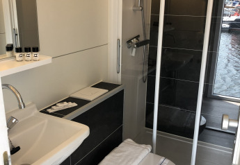 Moderne badeværelse på en husbåd ved Marina Parcs Naarden med bruser, toilet og lille håndvask.