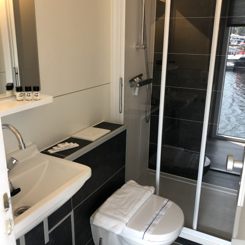 Moderne badeværelse på en husbåd ved Marina Parcs Naarden med bruser, toilet og lille håndvask.