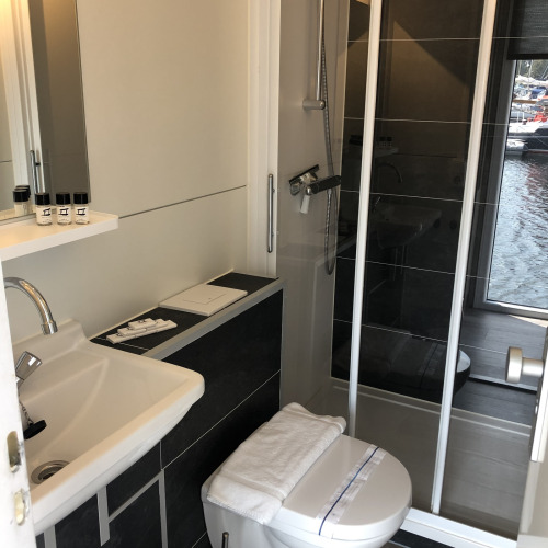 Baño moderno en una casa flotante de Marina Parcs Naarden, Países Bajos, con ducha y aseo compactos.