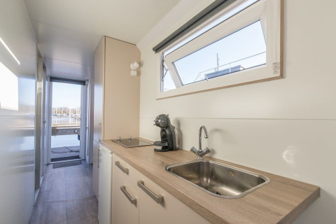Pequeña cocina moderna en la casa flotante Havenlodge de Marina Parcs Naarden, Países Bajos, con vista al puerto.