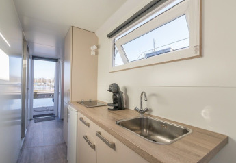 Modern kitchenette on the Havenlodge houseboat at Marina Parcs Naarden, Netherlands, with harbor view.