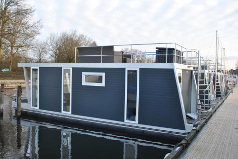 Moderne woonboot Havenlodge bij Marina Parcs Naarden in Nederland, aangemeerd aan een rustige steiger.