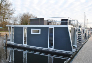 Moderne woonboot Havenlodge bij Marina Parcs Naarden in Nederland, aangemeerd aan een rustige steiger.