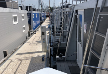 Houseboats docked along a floating pier at Marina Parcs Naarden in the Netherlands on a sunny day.
