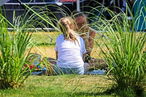 Twee mensen genieten van een picknick in het gras bij Sunlodge op vakantiepark 't Rheezerwold, Nederland.