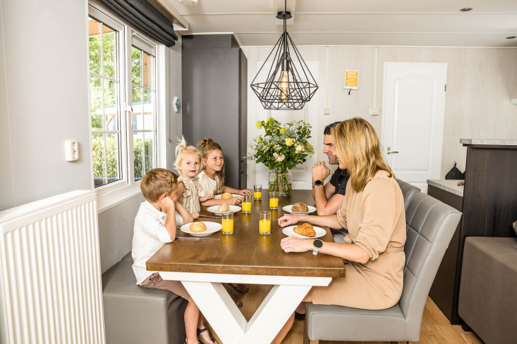Una familia desayuna junta en la mesa de un chalet luminoso en Kampeerdorp de Zandstuve, Países Bajos.