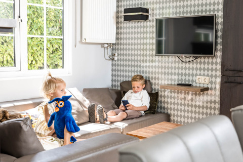 Twee kinderen ontspannen zich in een familiechalet bij Kampeerdorp de Zandstuve, Nederland, met knuffel.