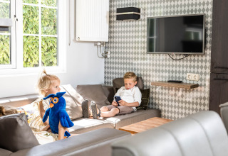 Deux enfants se détendent dans un chalet familial à Kampeerdorp de Zandstuve, Pays-Bas, l’un avec une peluche.