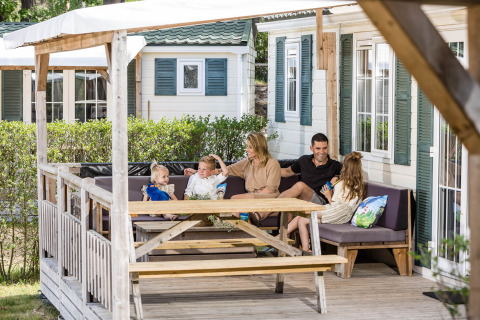 Een familie geniet samen op het terras van hun chalet in Kampeerdorp de Zandstuve in Nederland.