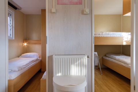 Interior view of a family chalet bedroom at Kampeerdorp de Zandstuve in the Netherlands with three beds.