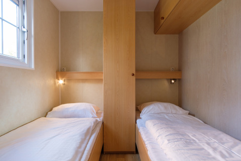 Dos camas individuales con ropa de cama blanca en una habitación de madera en Family chalet, Kampeerdorp de Zandstuve.