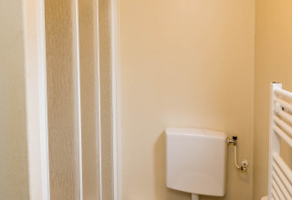 Bagno piccolo con doccia, wc, cestino e scopino in uno chalet familiare presso Zandstuve, Paesi Bassi.