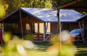 Tienda safari en Rheezerlodge, Kampeerdorp de Zandstuve en Países Bajos, rodeada de naturaleza y árboles.