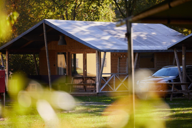 Tienda safari en Rheezerlodge, Kampeerdorp de Zandstuve en Países Bajos, rodeada de naturaleza y árboles.