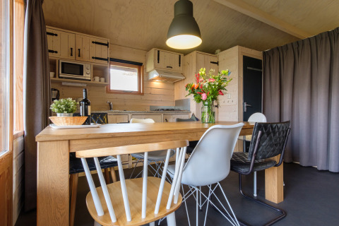 Moderne eethoek met houten tafel en verschillende stoelen in de keuken van Rheezerlodge, Nederland.