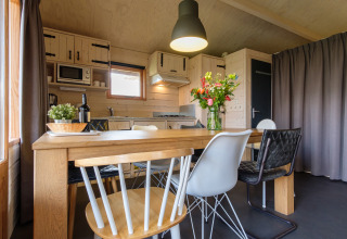 Moderne eethoek met houten tafel en verschillende stoelen in de keuken van Rheezerlodge, Nederland.