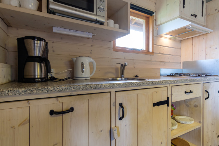Zona de cocina en Rheezerlodge, Kampeerdorp de Zandstuve, con cafetera, hervidor y cocina de gas.