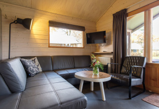 Moderne zithoek in Rheezerlodge safaritent bij Kampeerdorp de Zandstuve, Nederland, met bank en televisiescherm.