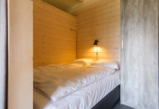 Cama confortable con sábanas blancas en una tienda safari en Rheezerlodge, Kampeerdorp de Zandstuve, Países Bajos.