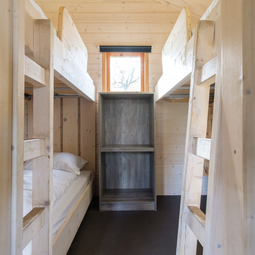 Camas literas y estantería de madera en una tienda safari en Rheezerlodge, Kampeerdorp de Zandstuve, Países Bajos.