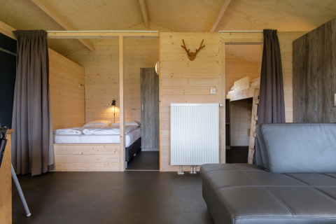 Interieur van een luxe safaritent bij Rheezerlodge met houten wanden, tweepersoonsbed en stapelbed.