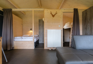 Interieur van een luxe safaritent bij Rheezerlodge met houten wanden, tweepersoonsbed en stapelbed.