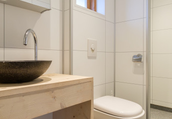 Baño moderno con inodoro suspendido, lavabo redondo y mueble de madera en una tienda safari en Rheezerlodge.