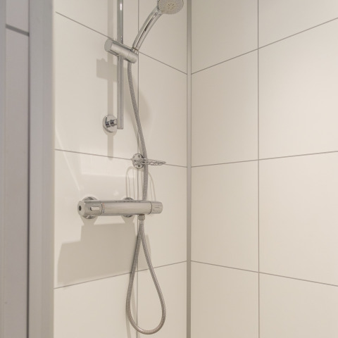 Moderne douche met verstelbare douchekop en witte tegels in Rheezerlodge, Kampeerdorp de Zandstuve, Nederland.