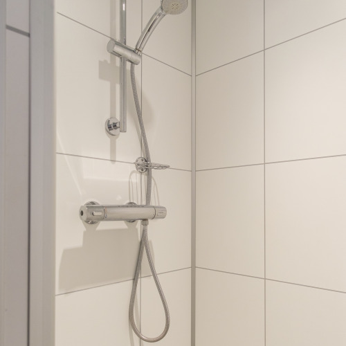 Ducha moderna con cabezal ajustable y azulejos blancos en Rheezerlodge, Kampeerdorp de Zandstuve, Países Bajos.