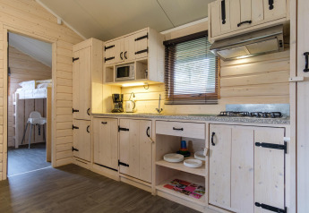 Cucina di lodge moderna con rivestimento in legno chiaro, fornelli a gas, microonde e letti a castello visibili.