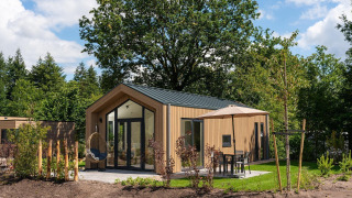 Modern Tiny Lodge with terrace and parasol at Veluwepark de Bosgraaf in the Netherlands, surrounded by nature.